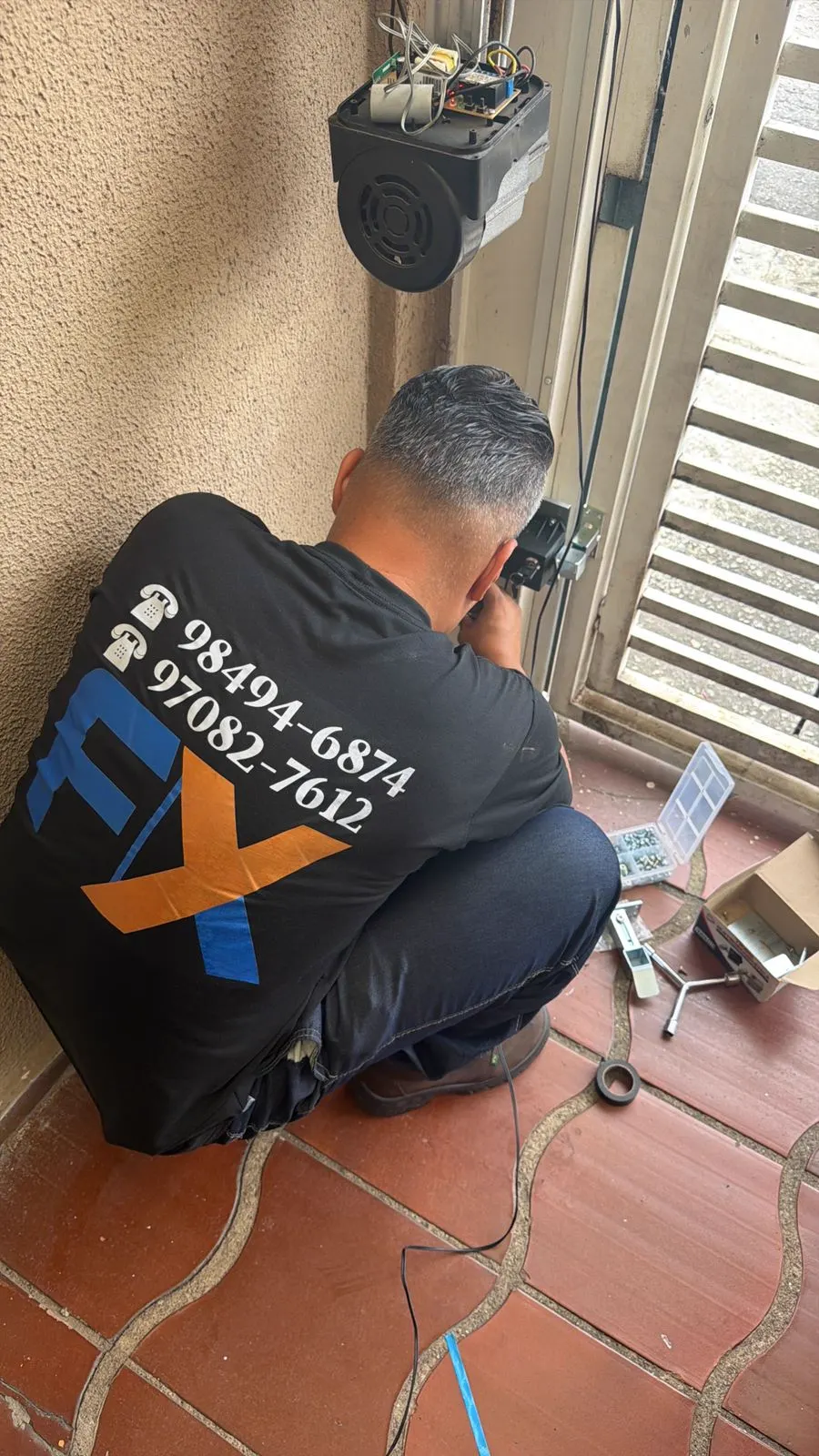Técnico da FX Manutenção Portões instalando motor de portão automático em residência